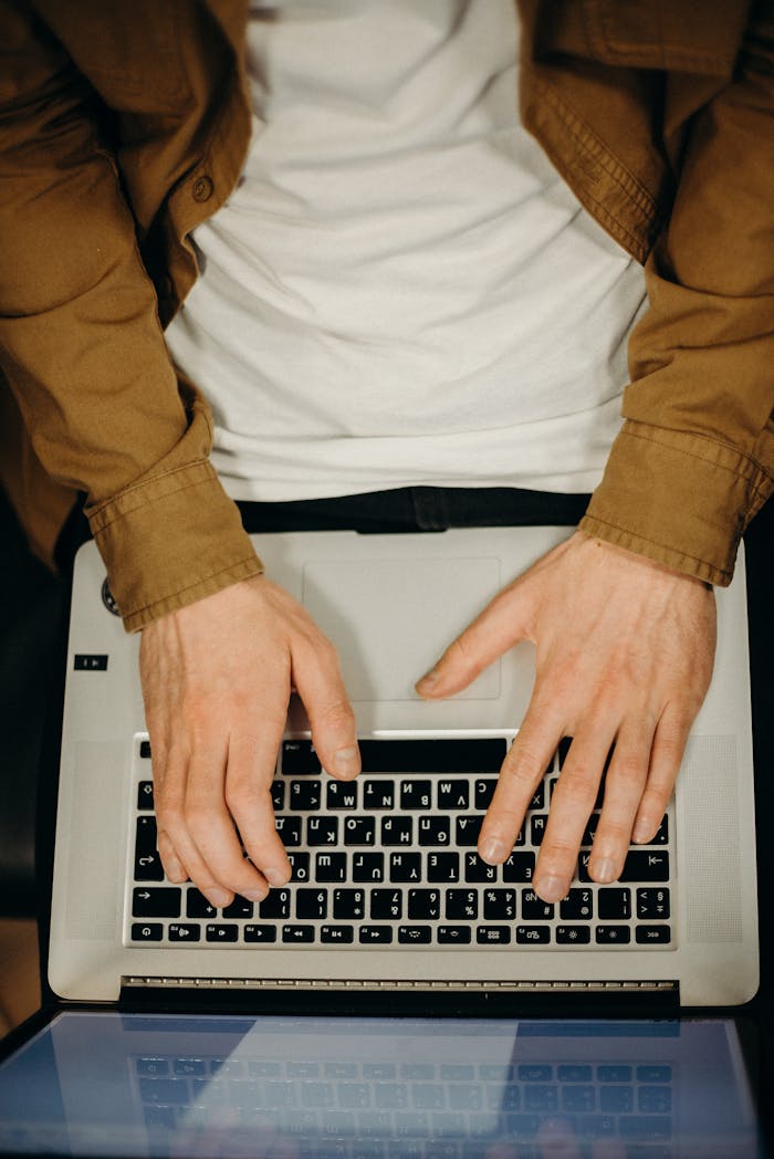 hero-img-02 Top view of hands typing on a laptop, showcasing technology and remote work.